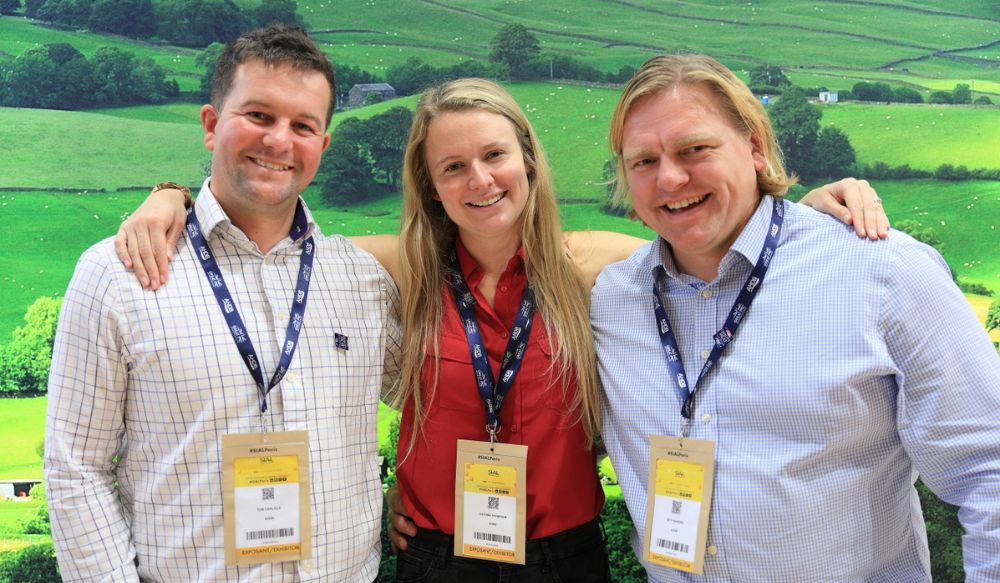 A man, woman and man wearing lanyards smiling at camera